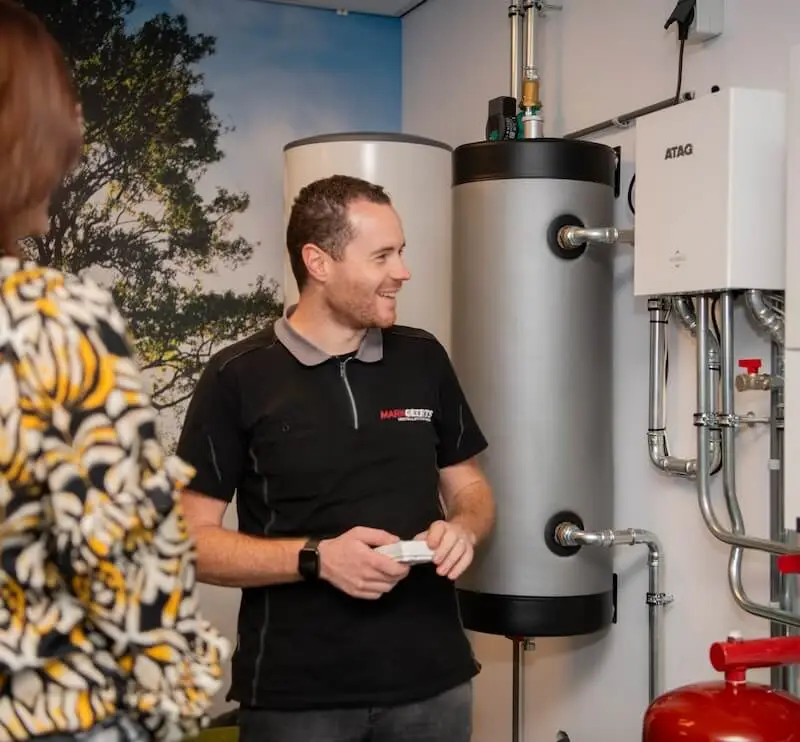 Een medewerker van Mark Geerts Installatiewerken legt de werking van een klimaatinstallatie uit aan een klant